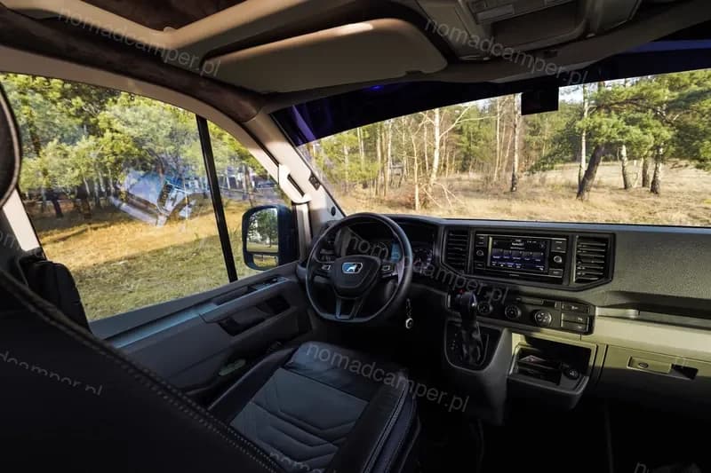 Kokpit kierowcy z panoramiczną szybą i lasem w tle