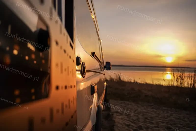 Kamper bokiem przy zachodzie słońca nad wodą