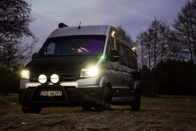 Kamper nocą z włączonymi reflektorami