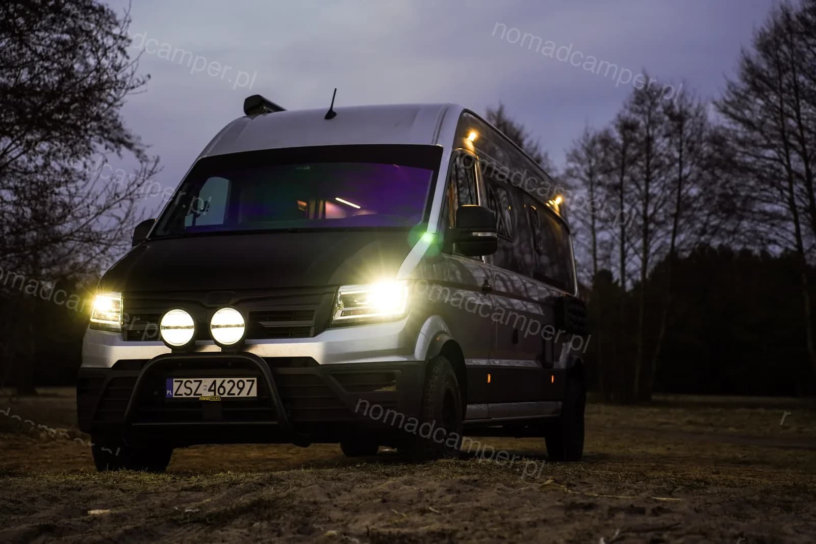 Kamper nocą z włączonymi reflektorami